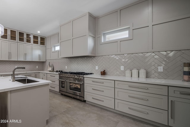 kitchen featuring light stone counters, glass insert cabinets, white cabinets, a sink, and double oven range