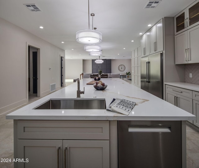 kitchen with a kitchen island with sink, built in refrigerator, visible vents, open floor plan, and gray cabinets