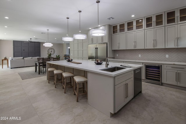 kitchen featuring wine cooler, stainless steel appliances, light countertops, a sink, and an island with sink