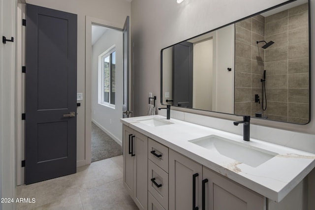 full bathroom with double vanity, tiled shower, a sink, and tile patterned floors