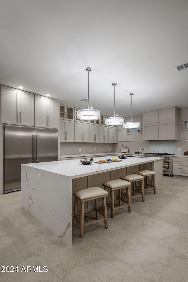 kitchen with a spacious island, a breakfast bar, hanging light fixtures, stainless steel built in fridge, and backsplash