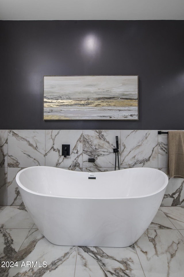 bathroom with marble finish floor and a freestanding tub