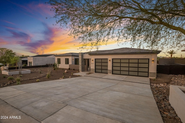 view of front of property featuring a garage, stone siding, concrete driveway, and stucco siding