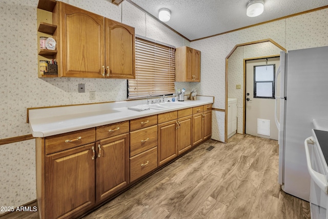 17124 E Fairway Dr, Mayer, AZ 86333 - kitchen featuring wallpapered walls, crown molding, light countertops, freestanding refrigerator, and light wood finished floors