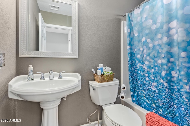 full bath with visible vents, a textured wall, and toilet