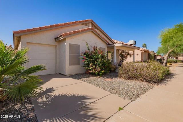 view of front of house with a garage, stucco siding, driveway, and a tile roof