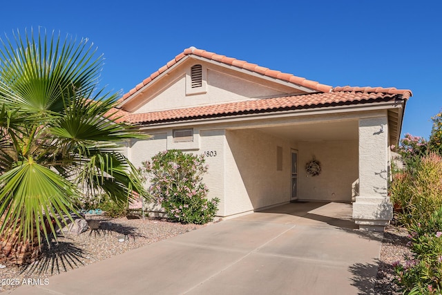 mediterranean / spanish home featuring stucco siding, a tile roof, and a carport