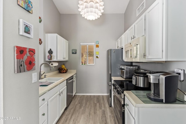 kitchen with stainless steel appliances, visible vents, white cabinetry, and a sink
