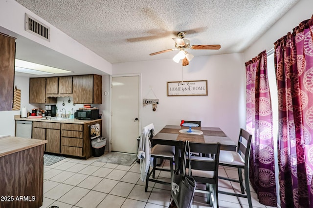 dining space featuring ceiling fan, sink, a textured ceiling, and light tile patterned floors