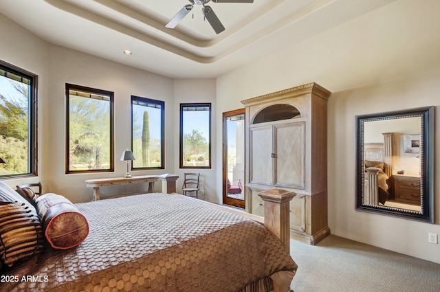 bedroom featuring ceiling fan, a raised ceiling, and light colored carpet