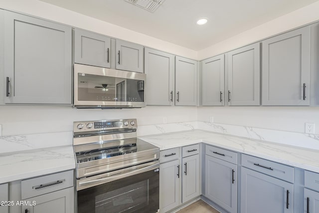 12813 W Paradise Dr, El Mirage, AZ 85335 - kitchen with stainless steel appliances, gray cabinetry, light stone countertops, and recessed lighting