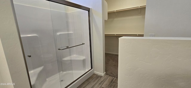 bathroom with wood-type flooring and a shower with door