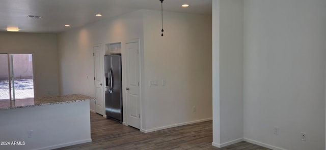 kitchen with light stone countertops, stainless steel fridge, and dark hardwood / wood-style floors