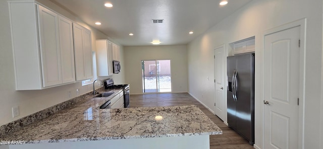 kitchen featuring stainless steel appliances, kitchen peninsula, light stone countertops, dark hardwood / wood-style floors, and white cabinets