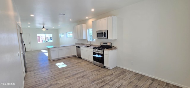 kitchen with stainless steel appliances, white cabinetry, sink, kitchen peninsula, and light hardwood / wood-style flooring