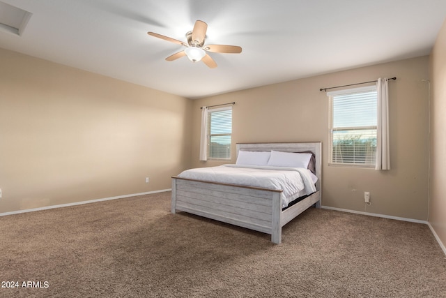 unfurnished bedroom featuring ceiling fan, dark carpet, and multiple windows