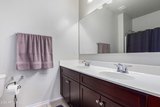 bathroom with dual bowl vanity, toilet, and tile floors