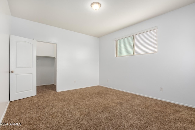 unfurnished bedroom featuring a walk in closet, light carpet, and a closet