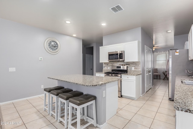 kitchen with a kitchen island, white cabinetry, ceiling fan, and stainless steel appliances