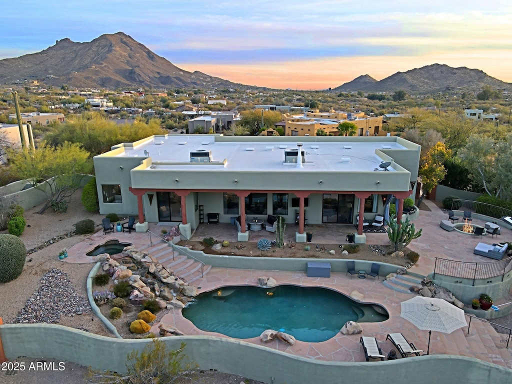 pool at dusk featuring a mountain view and a patio area