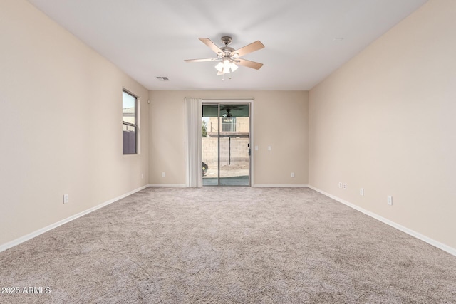 carpeted spare room with baseboards, visible vents, and ceiling fan