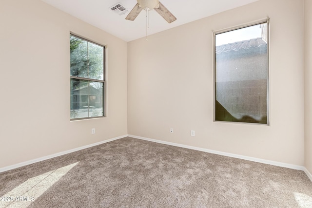 carpeted empty room with a ceiling fan, visible vents, and baseboards