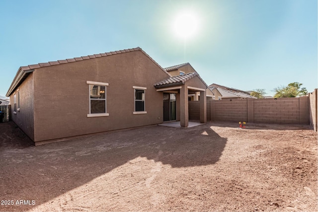 rear view of property with a patio area, a fenced backyard, a tile roof, and stucco siding