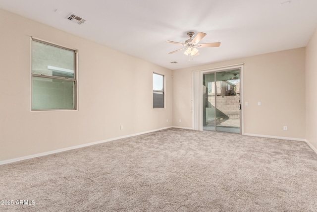 empty room with carpet, visible vents, ceiling fan, and baseboards