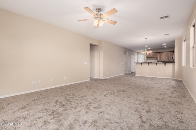 unfurnished living room featuring baseboards, visible vents, carpet flooring, and ceiling fan with notable chandelier