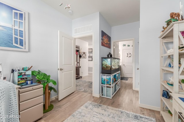 corridor featuring light wood-type flooring, baseboards, and visible vents