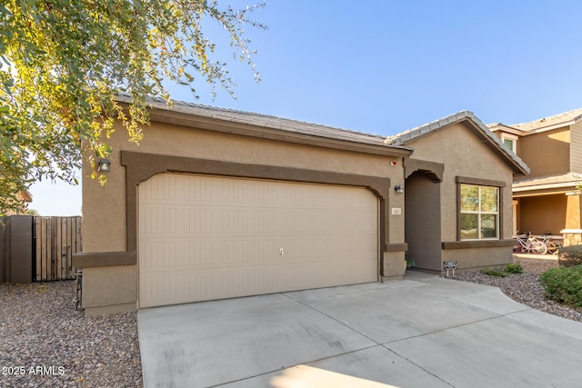 view of front facade with fence, a garage, driveway, and stucco siding