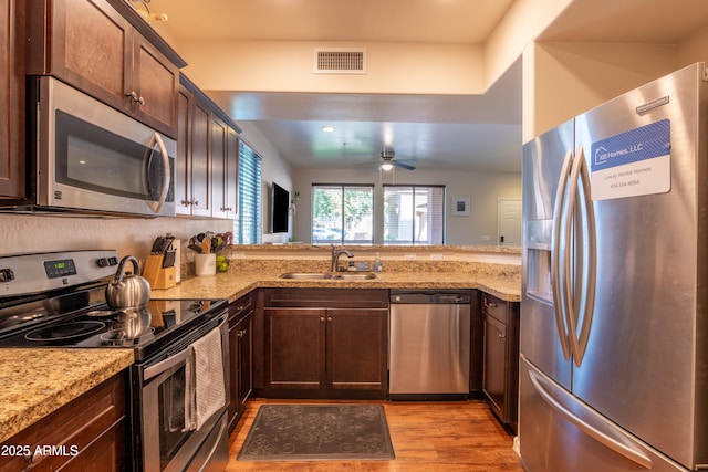 kitchen with light stone countertops, sink, ceiling fan, dark brown cabinets, and appliances with stainless steel finishes