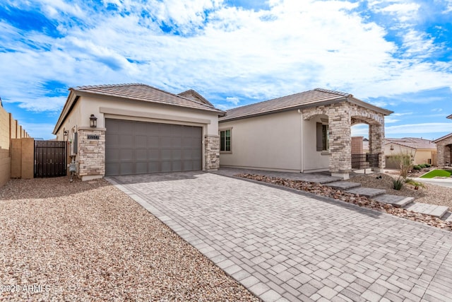 view of front of home featuring stucco siding, driveway, a tile roof, and an attached garage