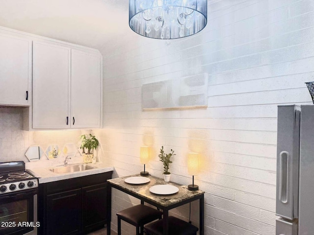 2150 W Missouri Ave Unit 120, Phoenix, AZ 85015 - kitchen featuring a sink, decorative backsplash, black / electric stove, white cabinets, and freestanding refrigerator