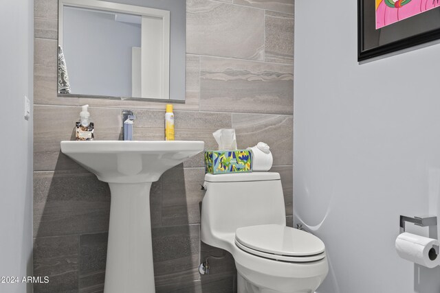 bathroom with toilet and tile walls