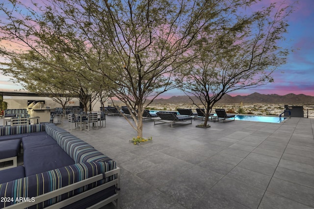 patio terrace at dusk featuring a mountain view, a bar, and an outdoor living space