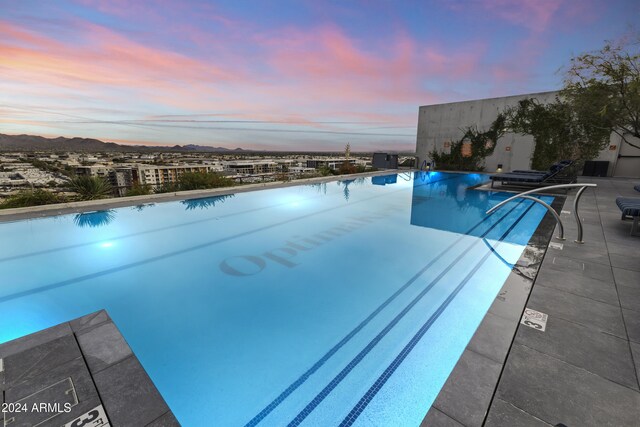 pool at dusk with a patio area