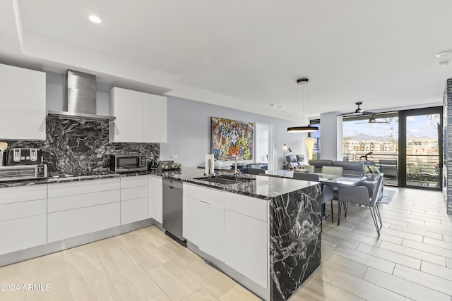 kitchen with white cabinets, wall chimney range hood, sink, dark stone countertops, and appliances with stainless steel finishes