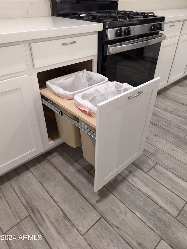 kitchen with white cabinetry, stainless steel stove, and light wood-type flooring