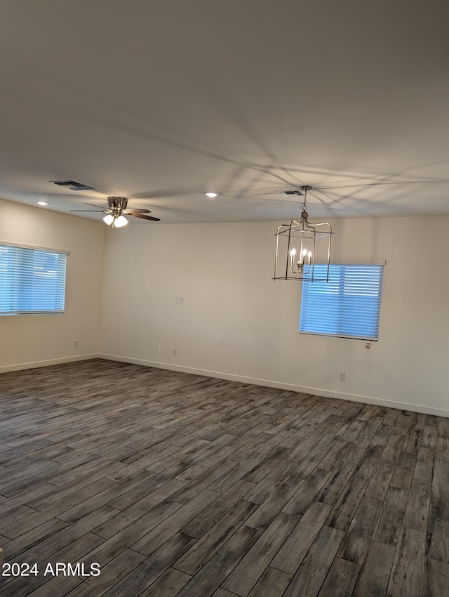 empty room featuring dark wood-type flooring and ceiling fan with notable chandelier