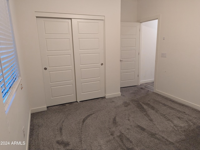 unfurnished bedroom with dark colored carpet and a closet