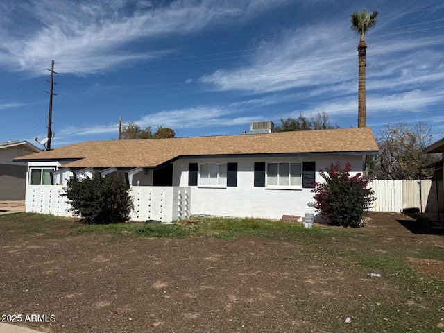 ranch-style home with concrete block siding, fence, and roof with shingles