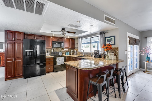 kitchen featuring kitchen peninsula, black appliances, light stone counters, and a textured ceiling