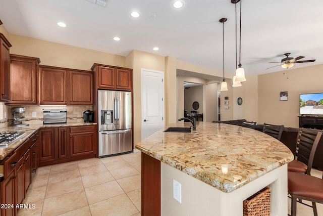 kitchen featuring appliances with stainless steel finishes, ceiling fan, sink, a large island with sink, and pendant lighting