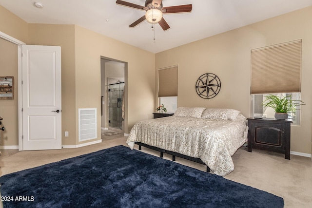 bedroom with ceiling fan, light colored carpet, and connected bathroom