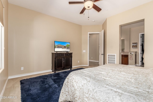 carpeted bedroom with ensuite bathroom and ceiling fan