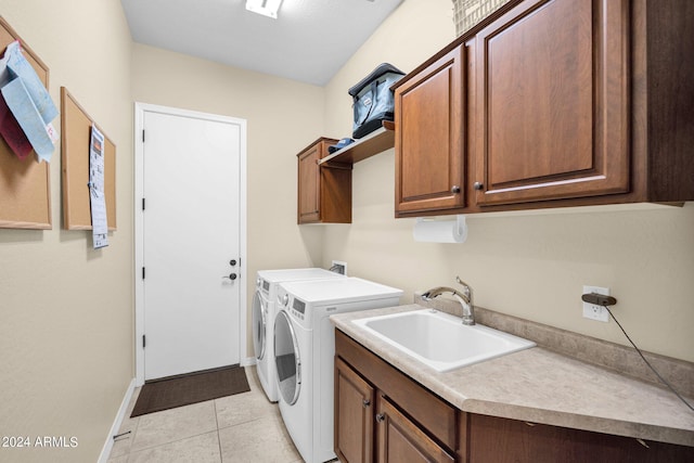 laundry room with washing machine and clothes dryer, sink, light tile patterned floors, and cabinets