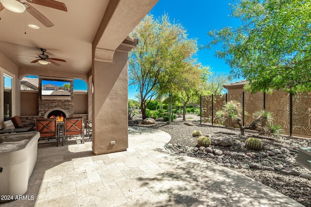 view of patio featuring an outdoor stone fireplace and ceiling fan