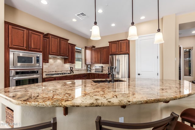 kitchen featuring stainless steel appliances, hanging light fixtures, a breakfast bar area, and a large island