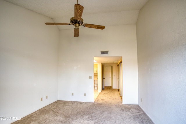 unfurnished room with ceiling fan, light carpet, and a high ceiling